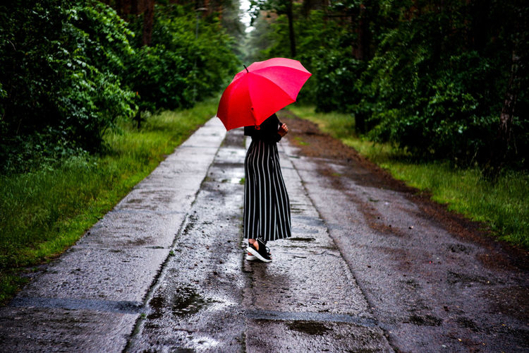 Woman walking on wet footpath during rainy season