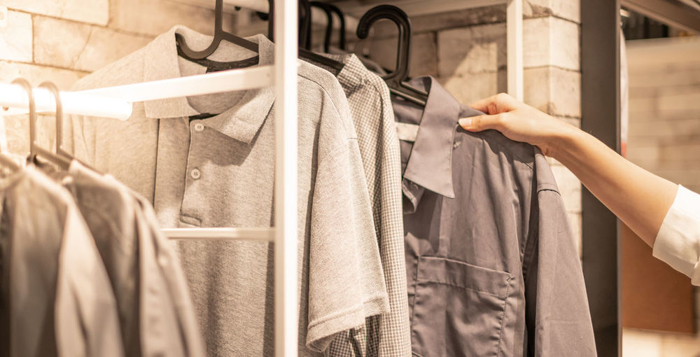 Male hand choosing clothes for checked pattern cotton polo shirt on the rack at a department store.