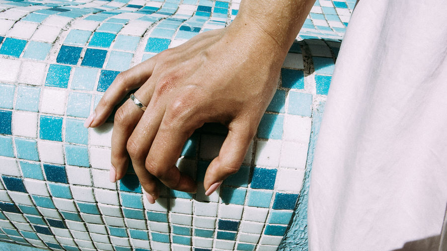 Cropped hand of woman on tiled wall