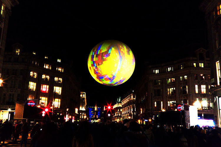 Illuminated hot air balloons in city against sky at night