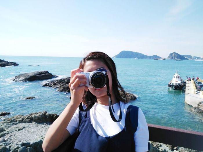 Portrait of woman photographing sea