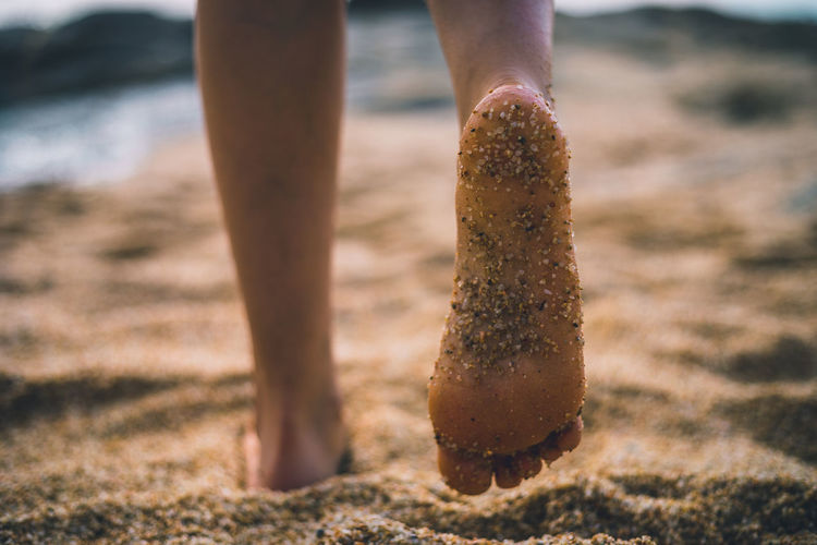 Low section of woman standing on sand at beach