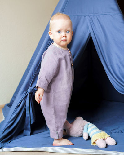 Adorable little child standing in play tent with toys