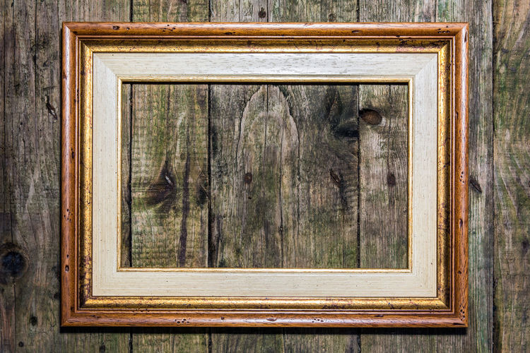 Close-up of picture frame mounted on wooden wall