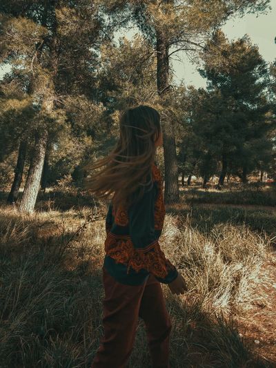 Woman looking away while standing in forest