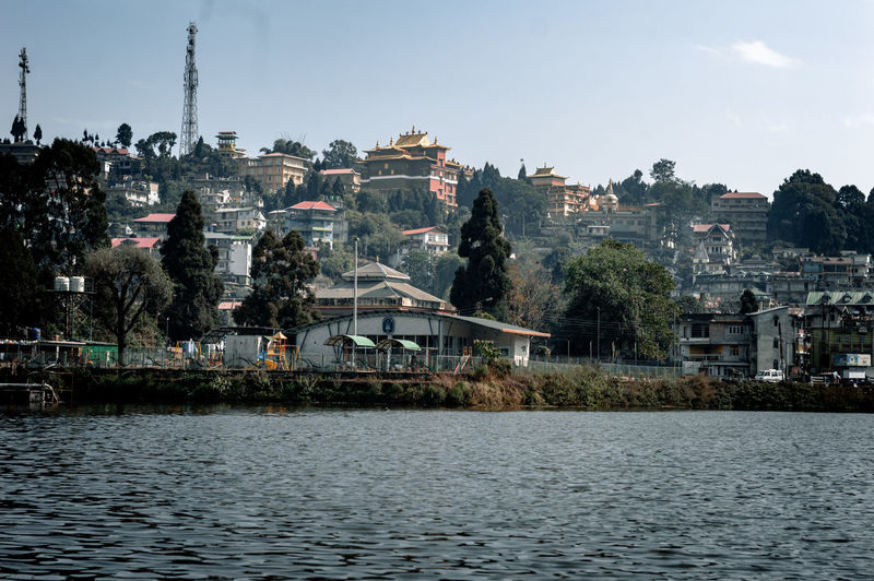 Buildings by river against sky
