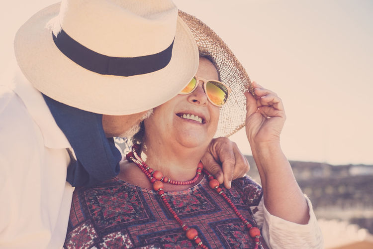Close-up of man kissing woman on cheek against sky