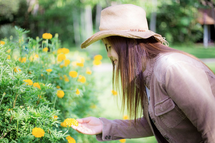 Side view of woman wearing hat against plants