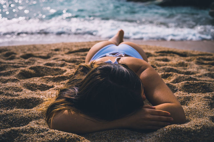 Young woman relaxing on sand at beach
