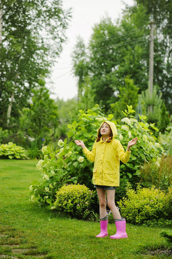 Full length of smiling girl standing by plants