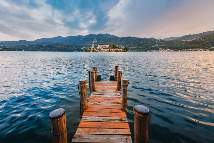 The island of san giulio with a wooden jetty in the foreground at sunset