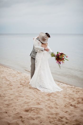 Bride and bridegroom embracing at beach during wedding ceremony