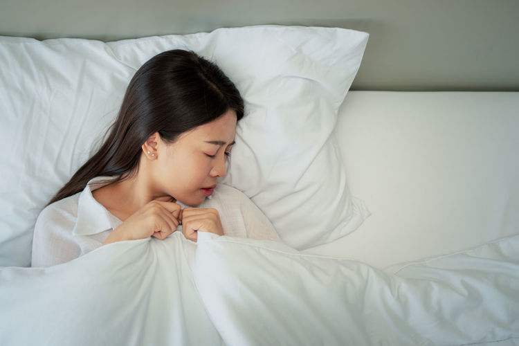 Midsection of woman sleeping on bed at home