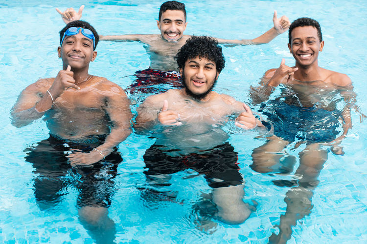 A group of young people in a pool smiling and gesturing