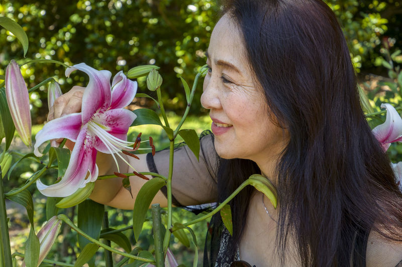 Close-up portrait of smiling woman with pink flowering plants