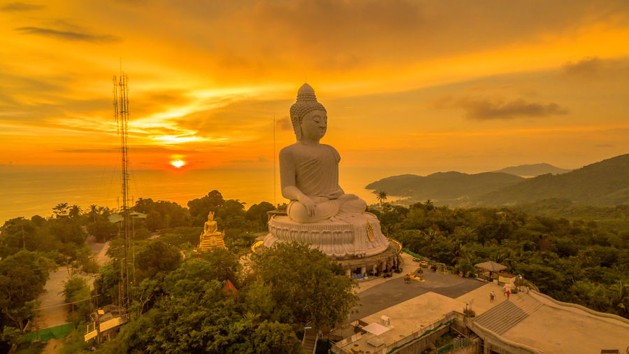 Statue of buddha against sky during sunset