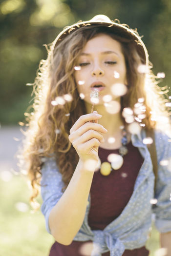 Young woman blowing dandelion