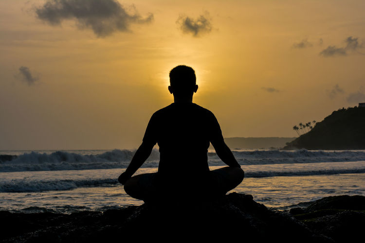 Silhouette of man meditating on beach