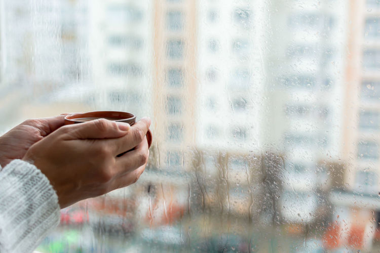 A girl with a mug in her hands at the window. morning coffee on a rainy day.