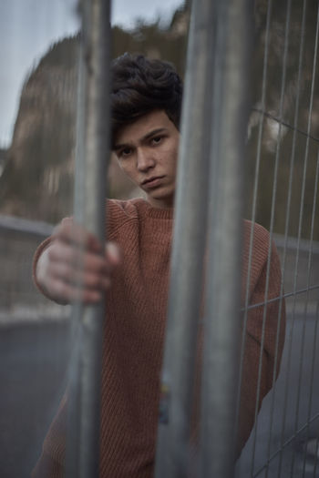 Close-up portrait of man looking through fence