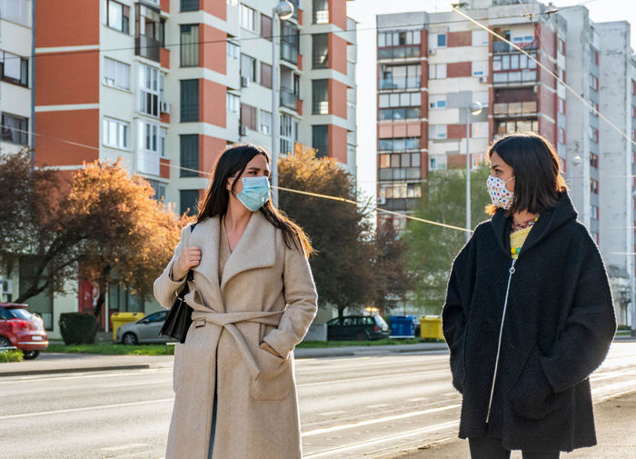 Two friends walking in city, wearing protective masks during corona virus epidemic, female, women.