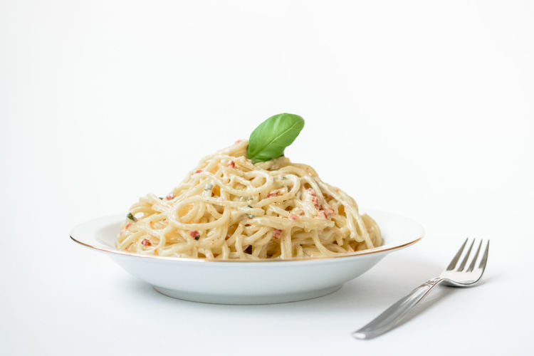 Close-up of noodles in plate against white background