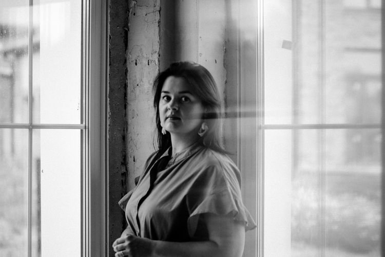Portrait of woman standing against window