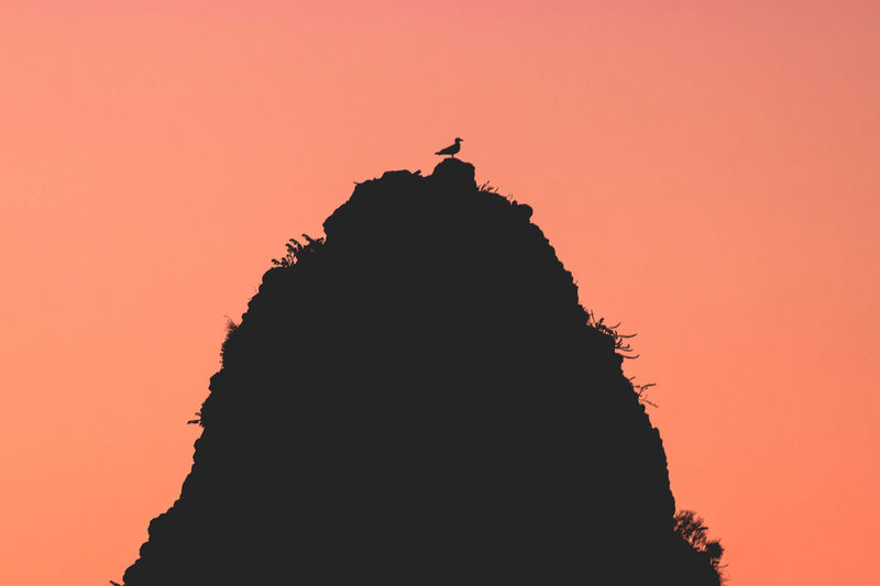 Silhouette rock formation against orange sky