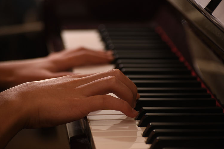 Close up teen's hand playing piano