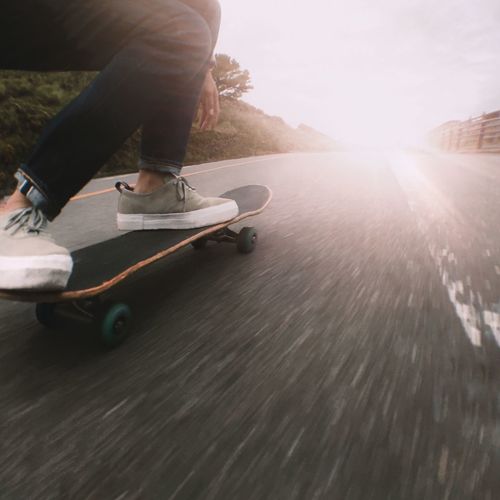 Low section of man skateboarding on skateboard against sky