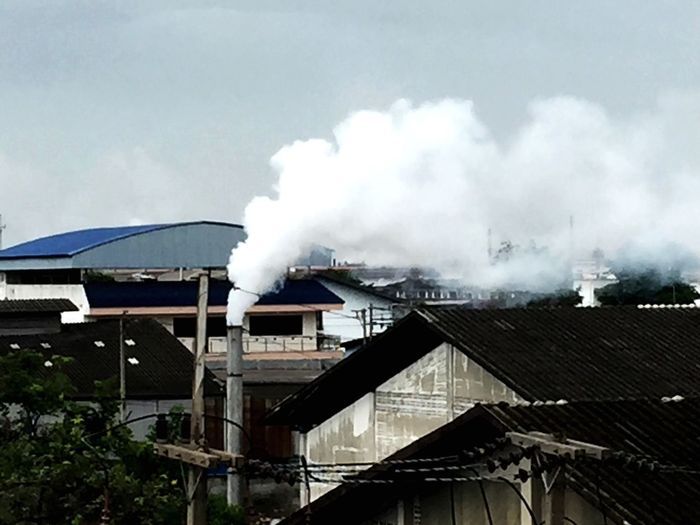 Smoke emitting from factory against sky