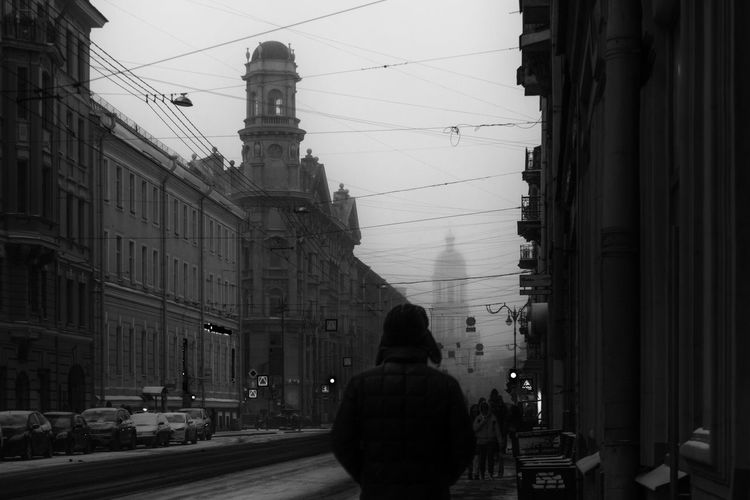 Rear view of woman walking on street amidst buildings in city