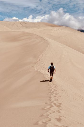 High angle view of man walking on sand dune in desert