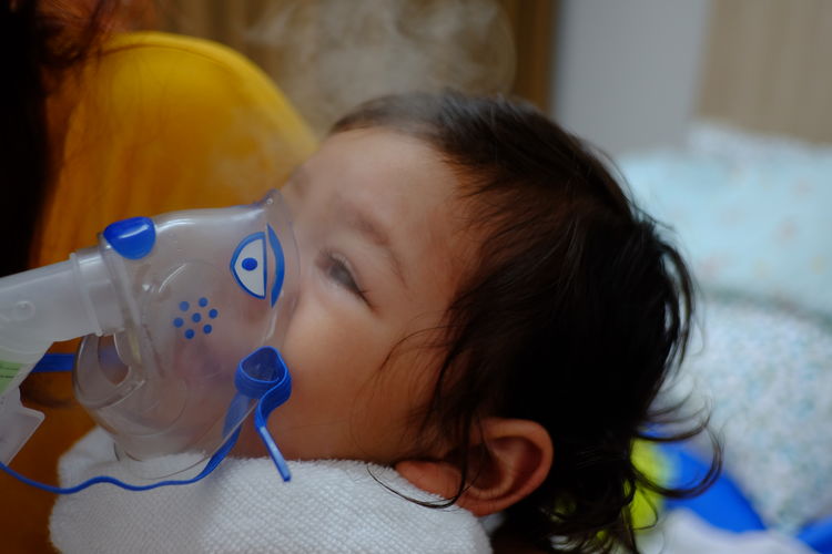 Close-up of cute girl with oxygen mask at hospital