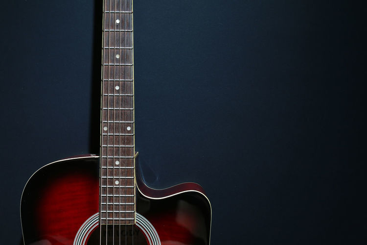 Close-up of acoustic guitar against black background