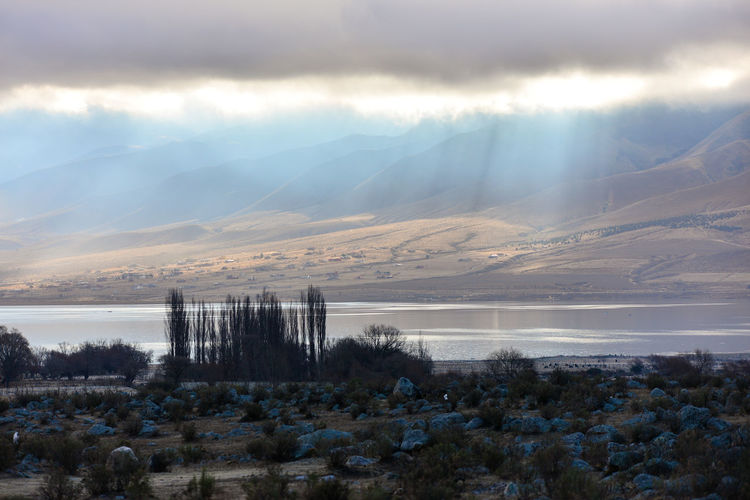 Sunlight streaming through clouds on river and mountains