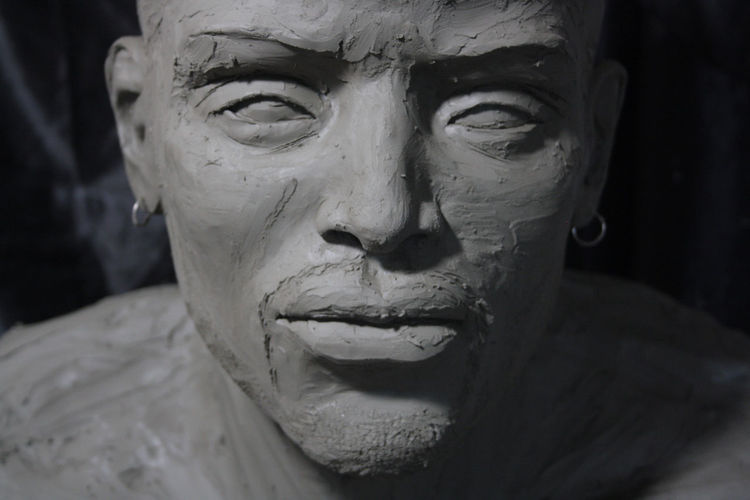 Portrait of a young african man. clay sculpture, in the process of creation.