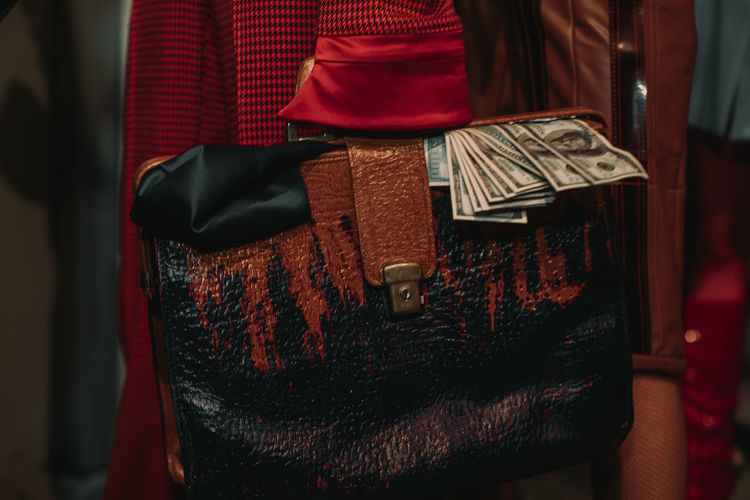 Female hand holding a large leather retro women's bag and paper dollars. women's fashion