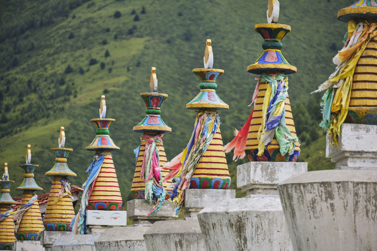 Traditional colorful buddhist statues with multicolored ribbons located in green valley in sichuan at daytime