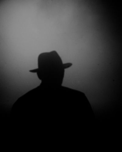 Rear view of silhouette man standing against dark wall