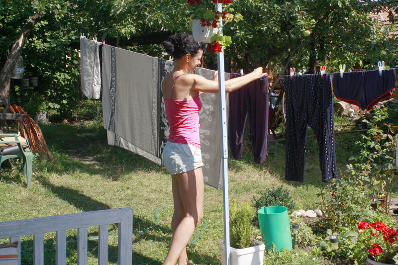 Woman adjusting clothes on line in yard