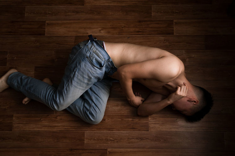 Young man lying on hardwood floor