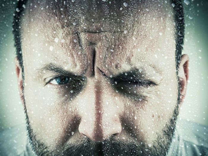 Portrait of man winking during snowfall