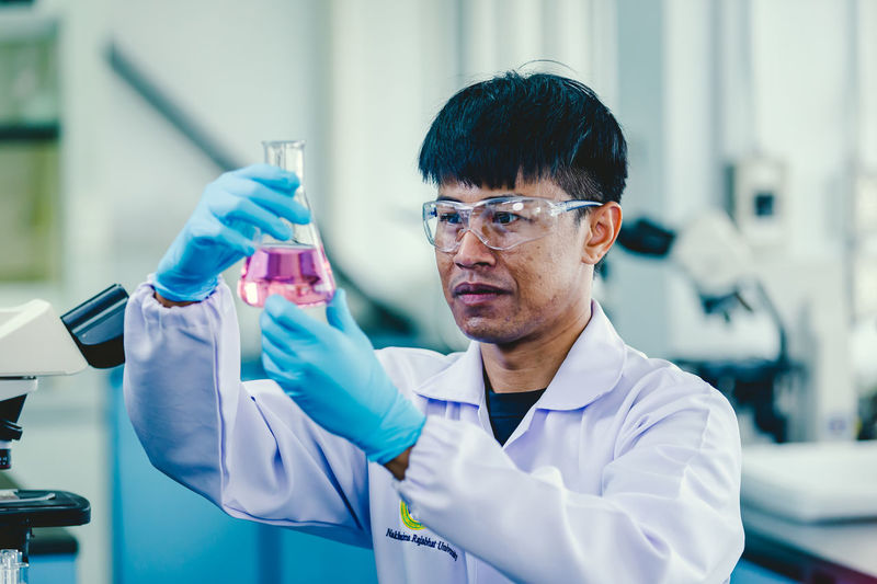 Asian male chemist wearing glasses and white lab working in laboratory