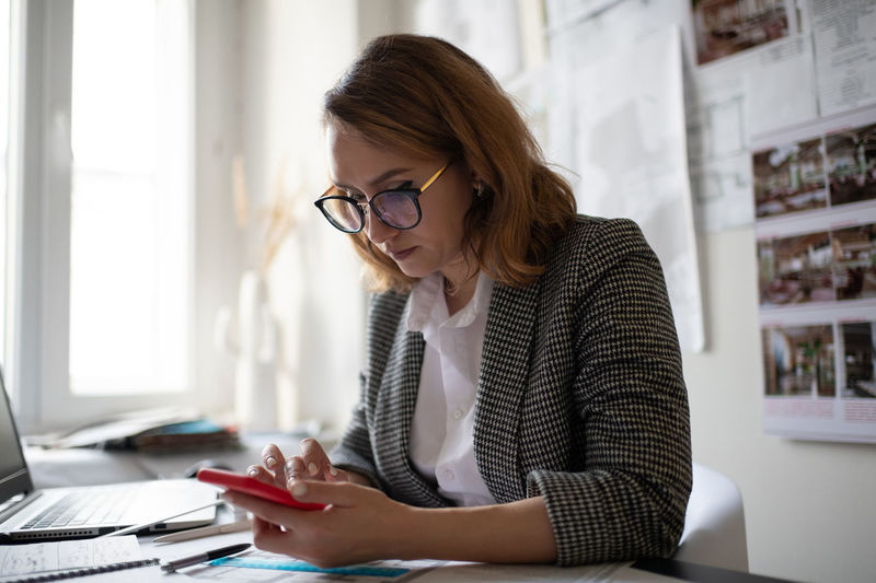 Serious businesswoman using smartphone in office