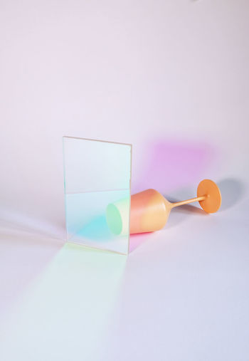 Close-up of multi colored glass on table against white background