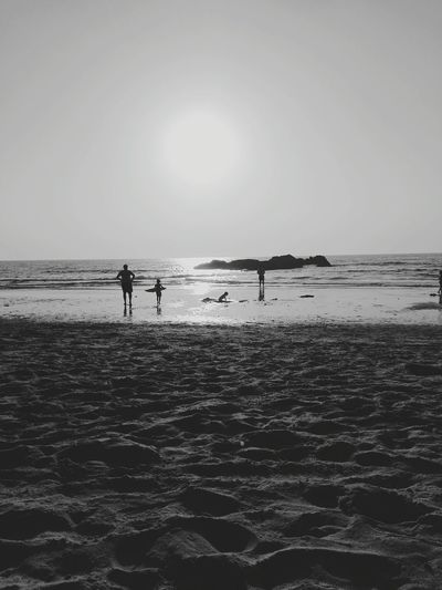 Silhouette people enjoying at beach against sky