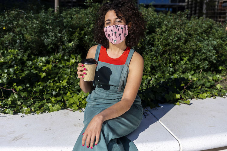 Portrait of woman wearing mask while holding coffee