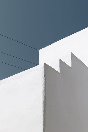Low angle view of white wall against clear sky