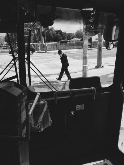 Side view of businessman walking on street seen through vehicle windshield